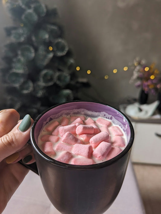 A woman holding a cup of hot chocolate with marshmallows