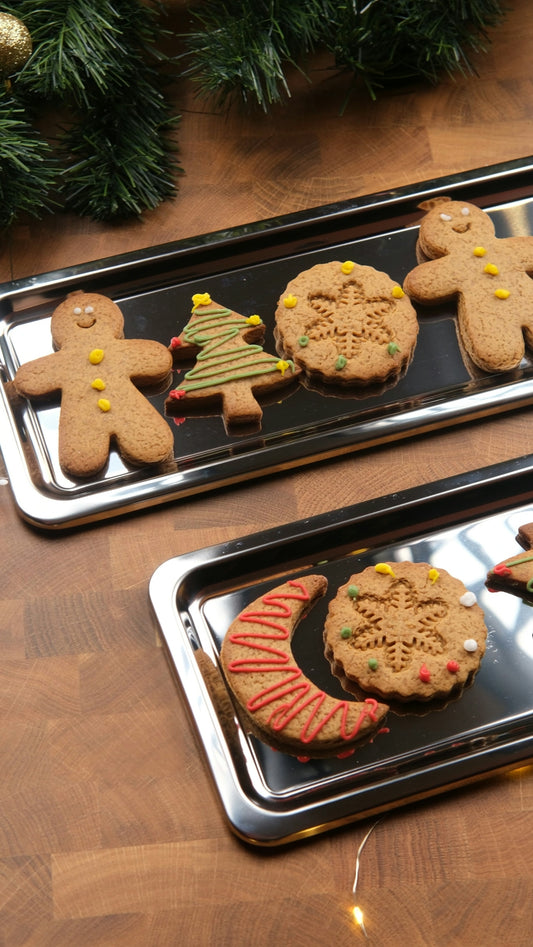 Christmas gingerbread cookies on trays with festive decorations.